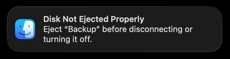 The macOS "Disk Not Ejected Properly" notification, reading: Eject "Backup" before disconnecting or turning it off.